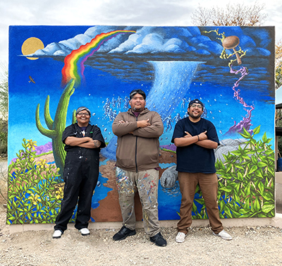 Photo of the artists in front of the large mural